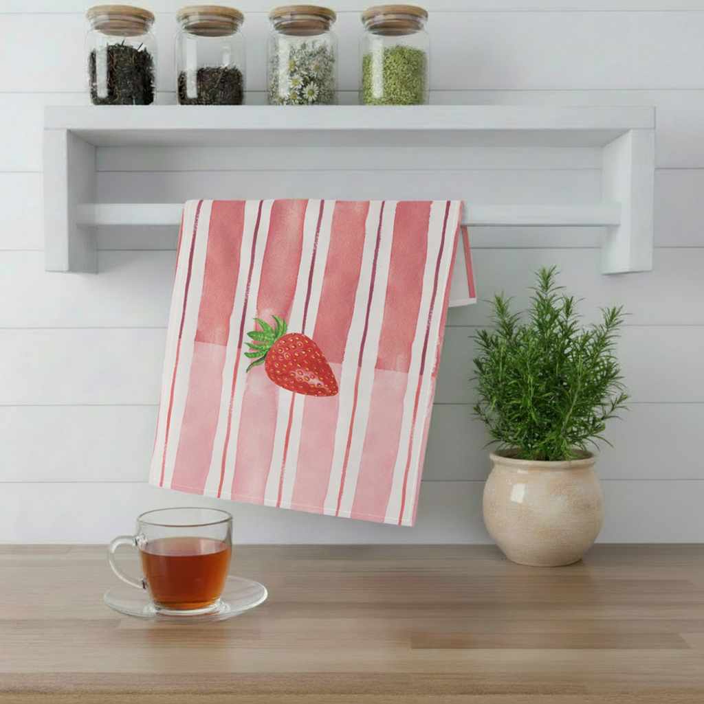 Striped towel with strawberry design hanging on a rack in a kitchen setting.